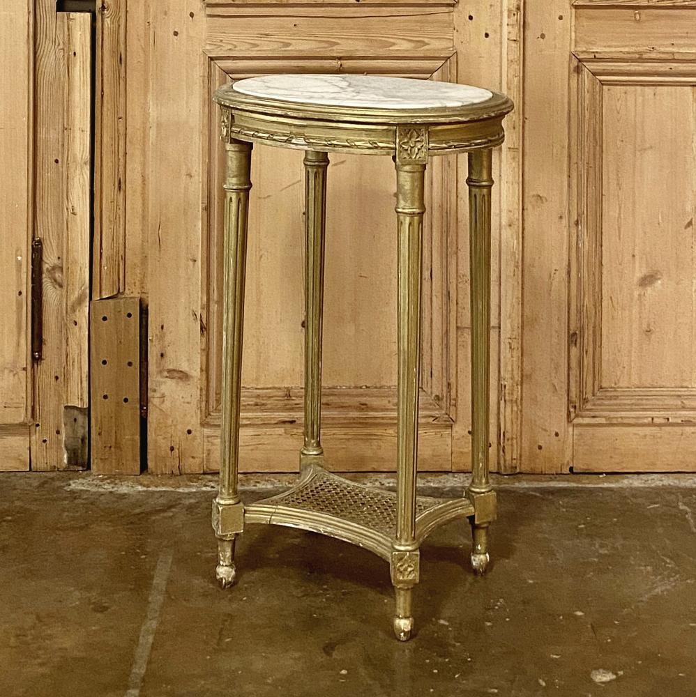 19th century French Louis XVI giltwood marble-top oval end table is a Classic example of the Classic style! Featuring a stately oval shape with marble on the top, its frame boasts acanthus rosettes and spiral ribbon trim. Tapered and fluted legs