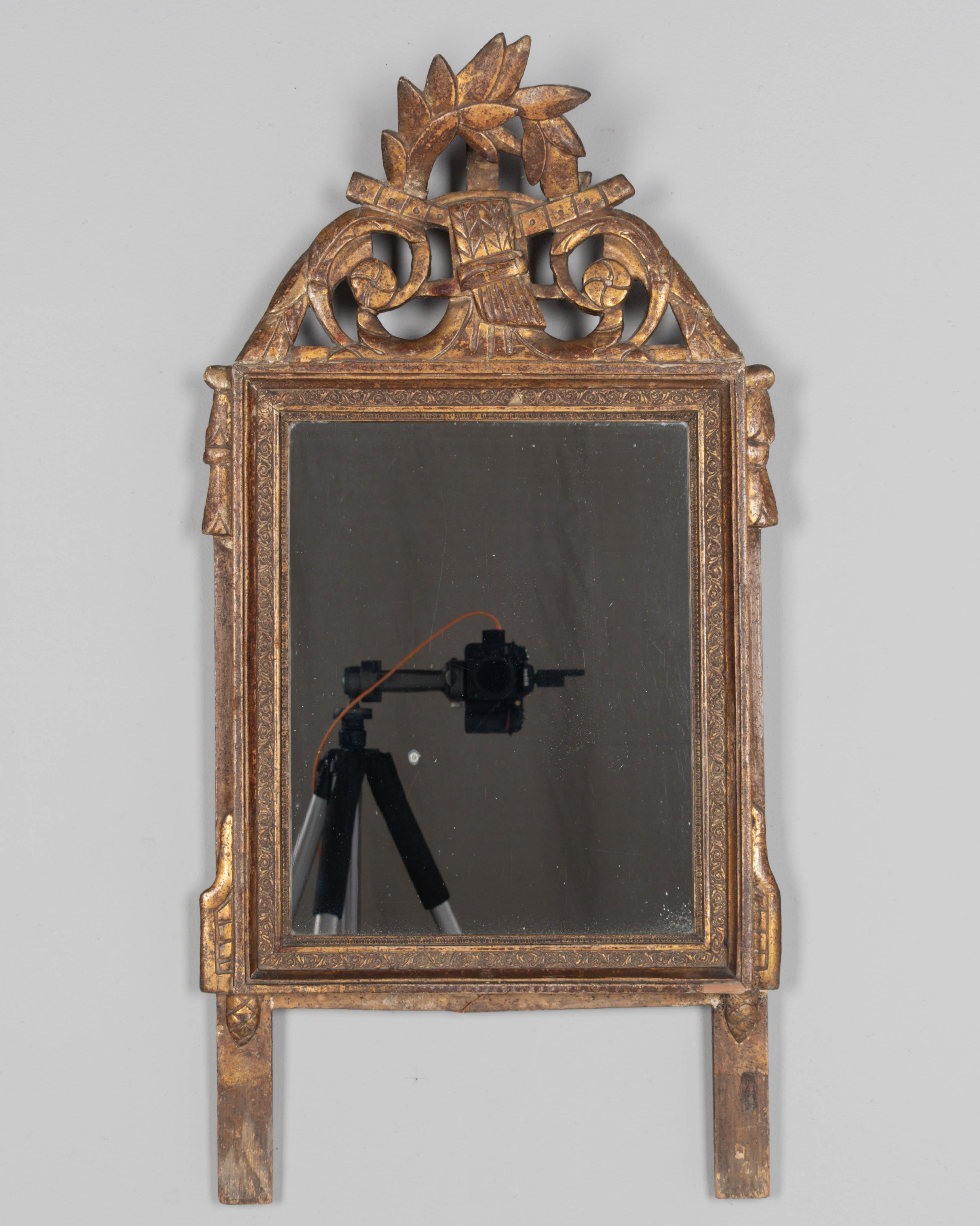 Miroir en bois doré provençal français de style Louis XVI du début du 19e siècle. Cimier sculpté à la main avec un tourbillon de guirlandes et de rosettes, des glands qui descendent sur les côtés. Finition dorée chaleureuse avec une belle patine. Le