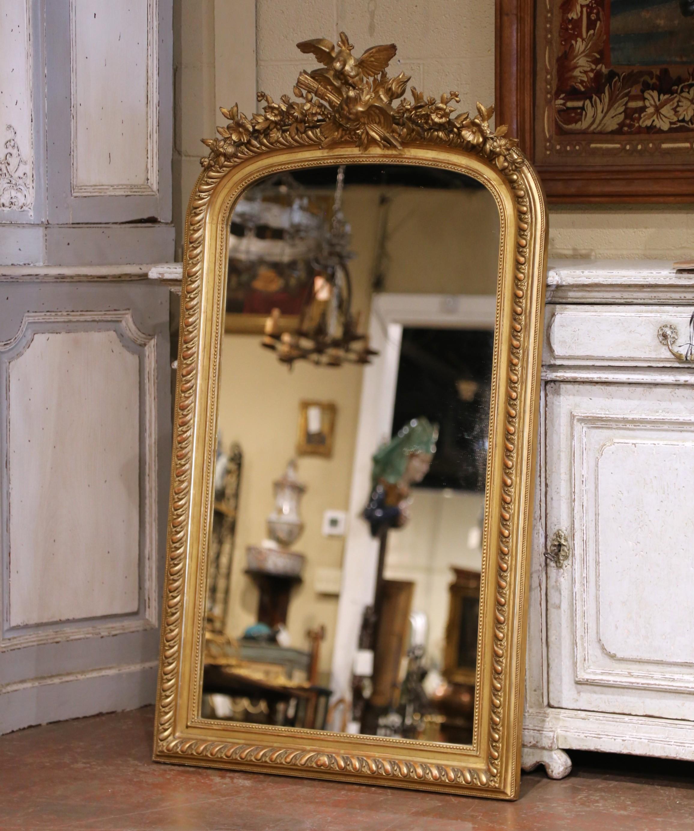 Porta calore e romanticismo in ogni spazio con questo raffinato specchio da parete in legno dorato francese. Realizzato in Francia intorno al 1870, questo pezzo antico presenta una cornice graziosamente arcuata, intagliata a mano con modanature a