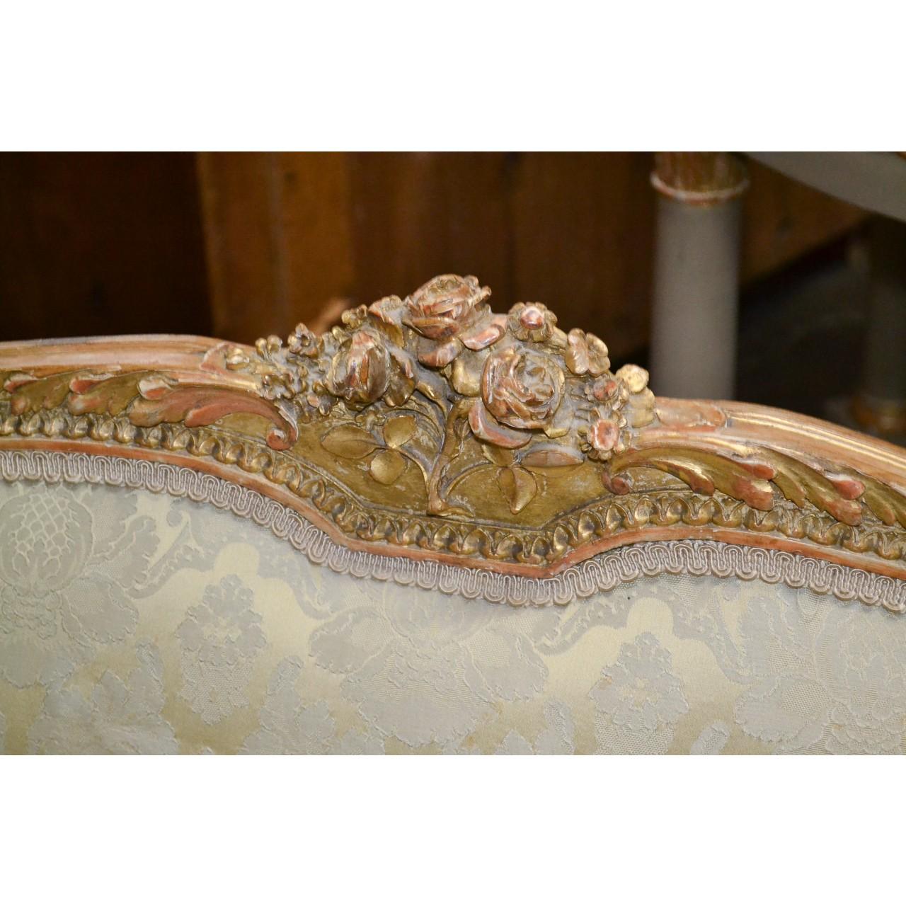 Beautifully elegant 19th century French Louis XVI style giltwood and upholstered settee or loveseat. The shaped crest-rail with a hand-carved rose cluster and two crown finials. The arms with finely carved acanthus leaves and raised on fluted and