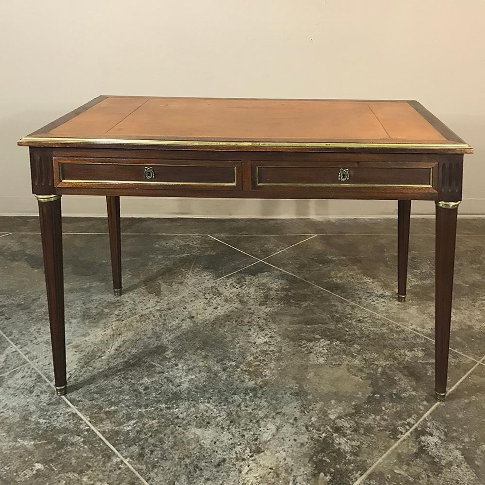 19th century French Louis XVI leather top desk, or bureau plat, makes the perfect choice for home offices or as a secondary desk at your business. A highly restrained interpretation of the style, it was crafted in mahogany, and features brass rings