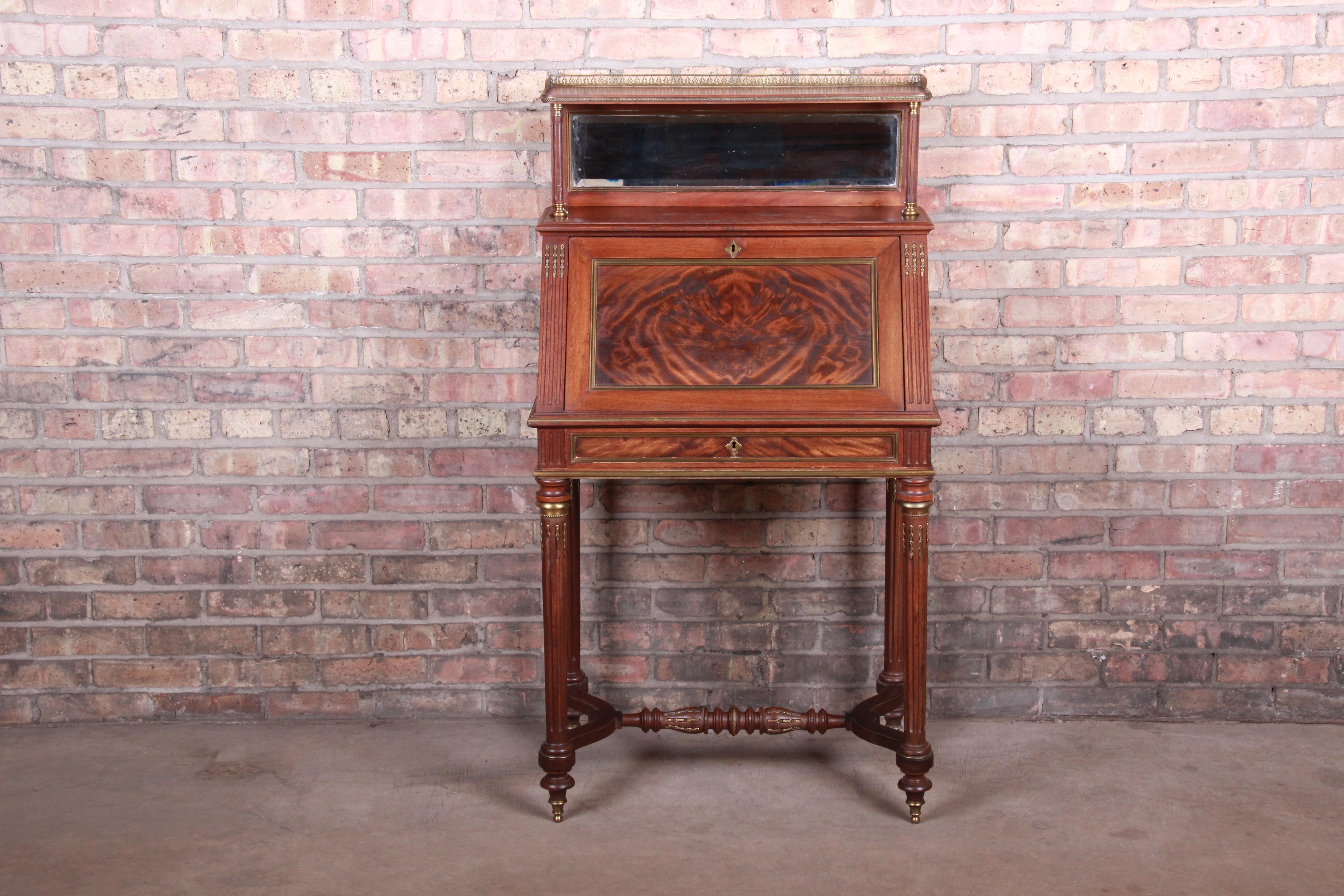 A gorgeous French slant front secretary desk

France, 19th century

Flame mahogany, with brass gallery and accents, beveled mirror, and leather writing surface.

Measures: 26.88