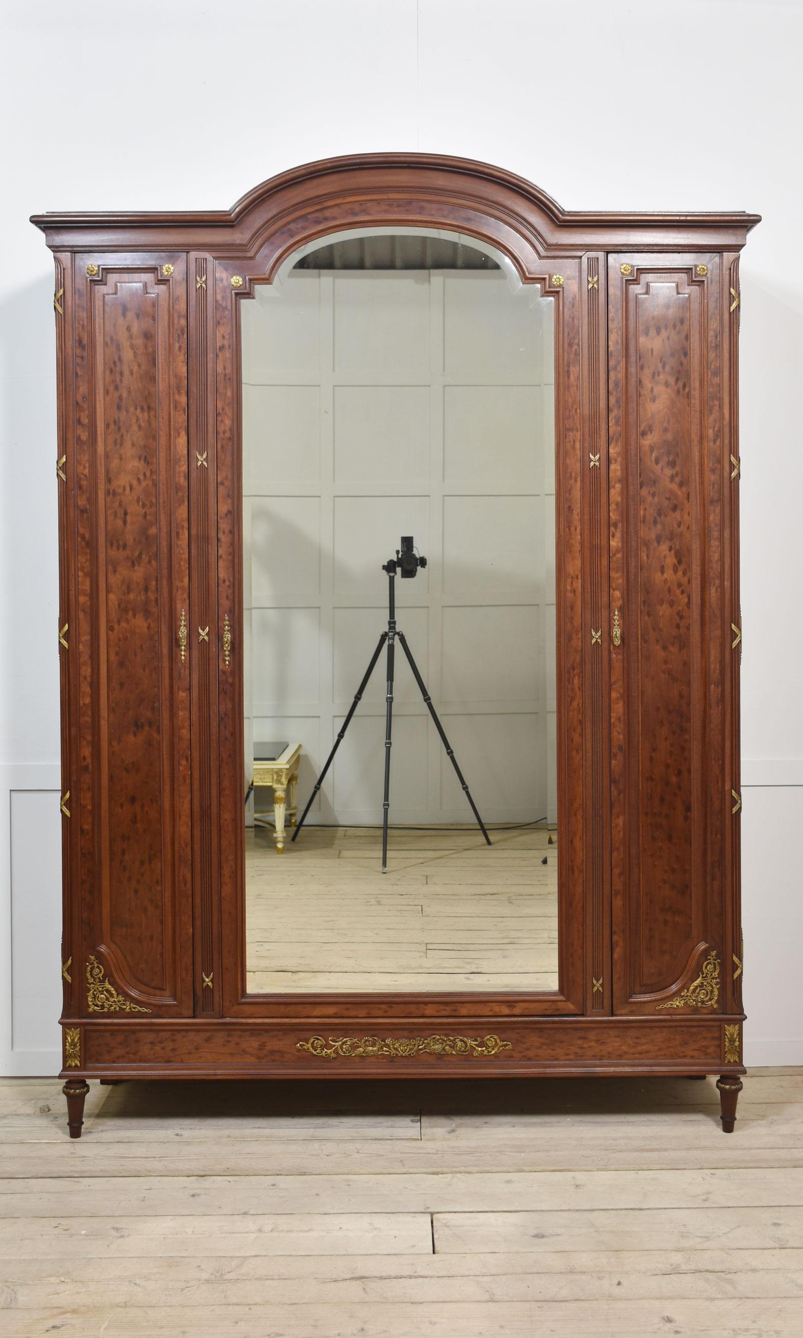 19th Century French Louis XVI Mahogany and Gilt Bronze Armoire, the dome top above a large central bevelled mirror door flanked by two narrow well-figure panelled doors. Opening to reveal a large adjustable shelved interior. The shelves can be