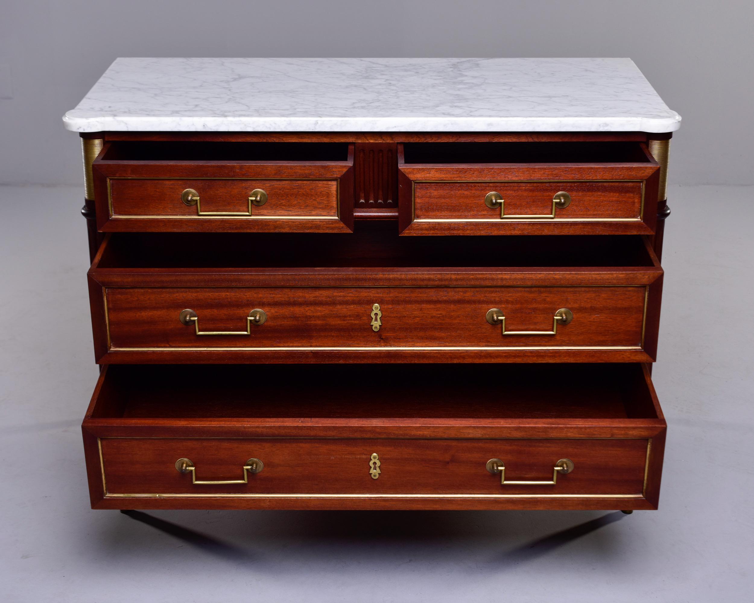 Circa 1880s Louis XVI style four drawer commode in mahogany features brass hardware and trim, turned legs, a white marble top and new, professionally applied finish. Unknown maker.