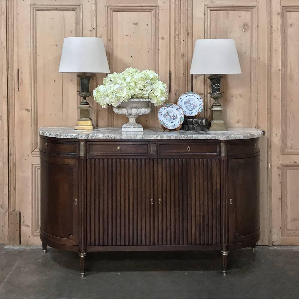 19th century French Louis XVI marble-top buffet features rounded sides that are so traffic friendly, with a tambour style façade that provides clean neoclassic lines. Capacious cabinets include pie-shaped compartments on both sides, and on top is a