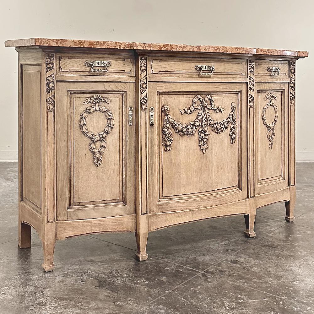 19th Century French Louis XVI Marble Top Buffet in Stripped Oak is an intriguing design conceived during the early years of the Art Deco Period, with broad, arched aprons and tapered, faceted legs supporting the casework which features a broad,