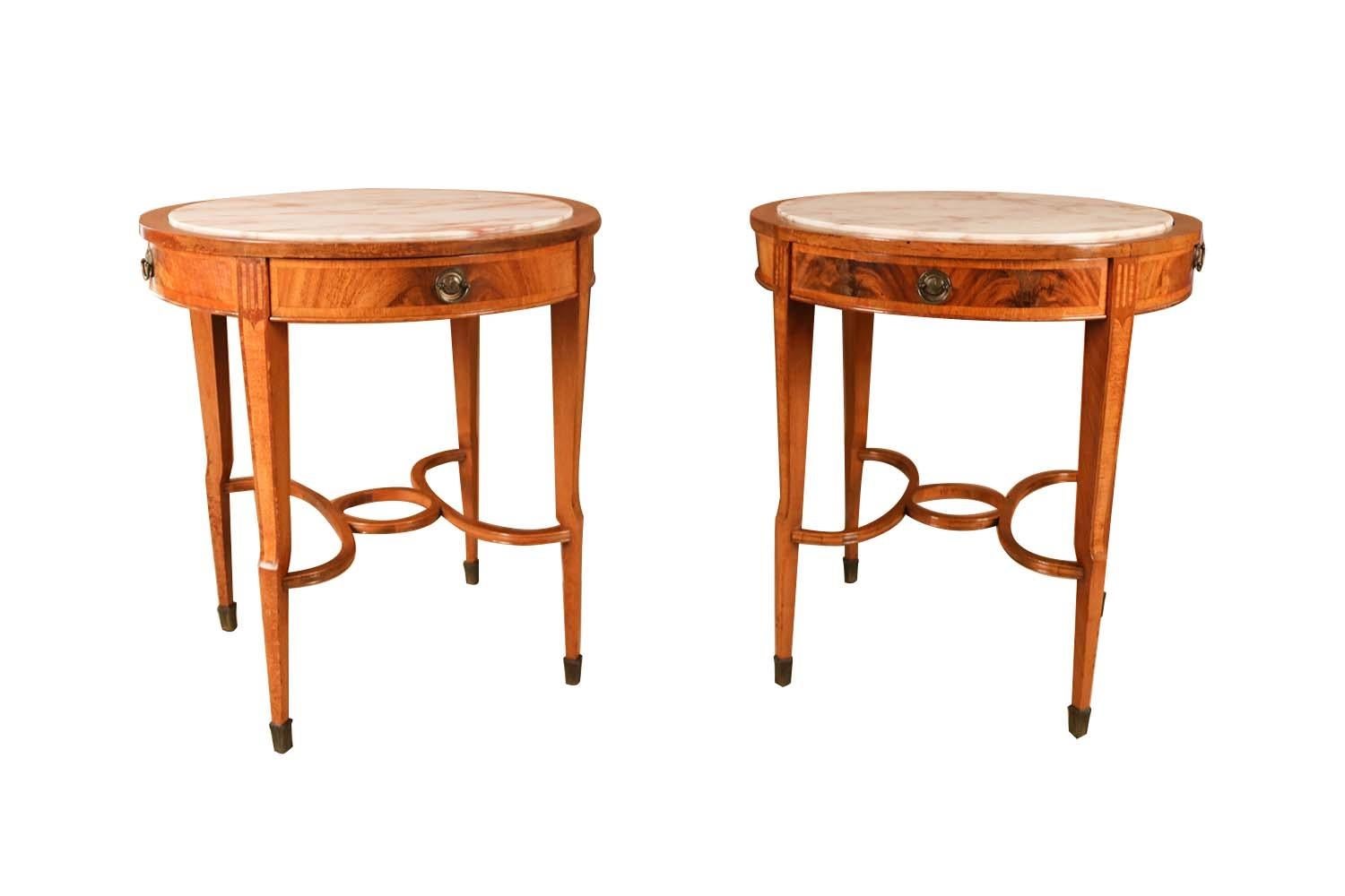 A pair of 19th century French Louis XVI marble top accent tables. These spectacular tables are composed of a mixed wood frame with a beautiful grey, white, and dark rose inset marble top and a center drawer. This pair of exquisite tables feature a