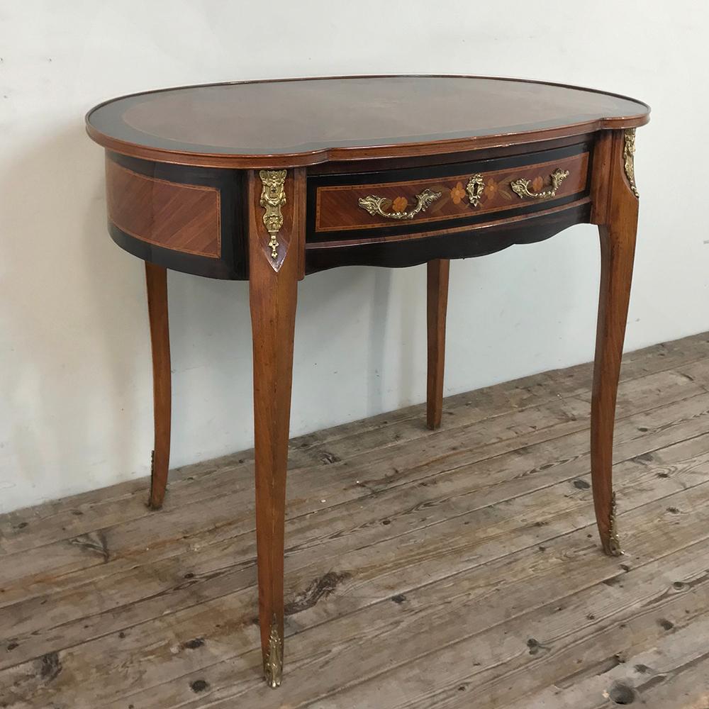 19th century French Louis XVI marquetry writing table was fashioned in a kidney shape, and features subtly scrolled legs fitted with cast bronze ormolu mounts at the top. Ebonized walnut surrounds the panels on the sides and top, separated from the