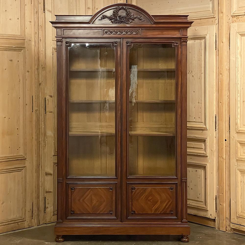 19th Century French Louis XVI neoclassical mahogany bookcase is a stately example of the revival of the ancient Greek and Roman architecture that has proved to be sublimely timeless! Straight, rectilinear lines are enhanced by a boldly molded arched
