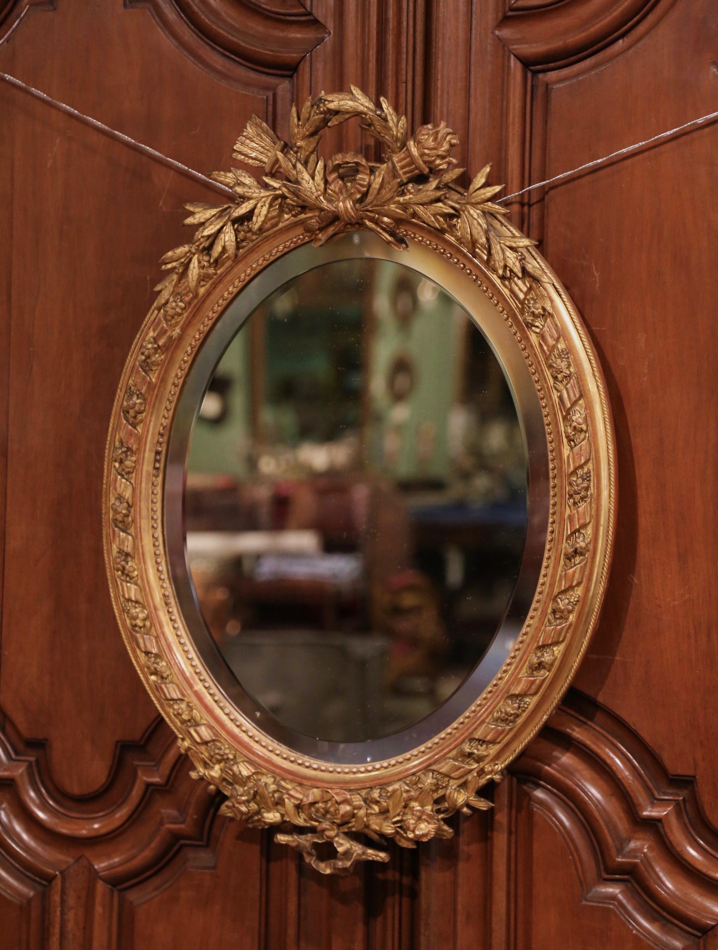 Decorate a powder room or entry with this elegant antique wall mirror. Crafted in France circa 1860 and oval in shape, the carved frame is decorated with floral motifs including carved torch and laurel motifs at the pediment, and embellished with a