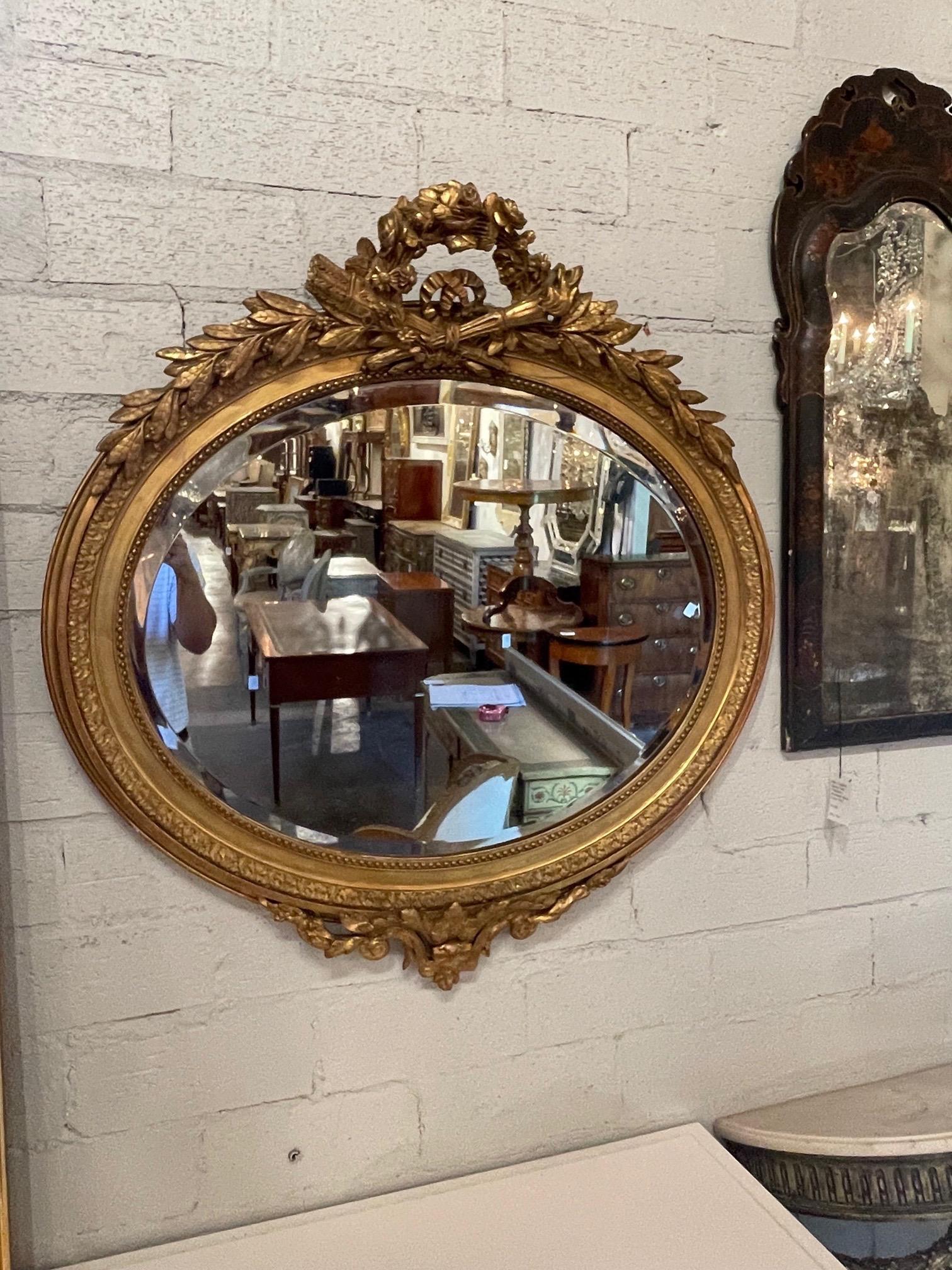 Exquis miroir ovale biseauté en bois doré de style Louis XVI français du 19e siècle. Ce miroir présente une sculpture exceptionnelle. C'est une déclaration impressionnante !
