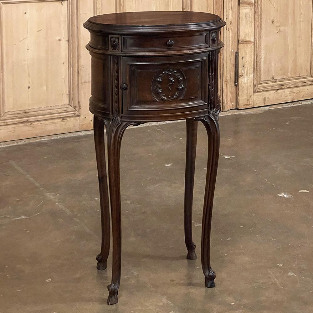 19th century French Louis XVI oval nightstand is a gracefully executed transitional piece, combining a neoclassical essence with the elegance of four subtly scrolled cabriole legs and an oval casework to create a wonderfully versatile companion for