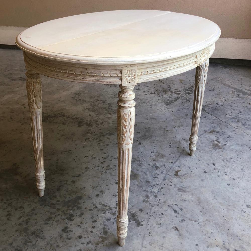 19th century French Louis XVI oval painted center table works equally well as an end or side table! Classically-inspired lines include spiral ribbon bordering around the oval apron centered with sunflower rosettes. Rosettes appear also on the plinth