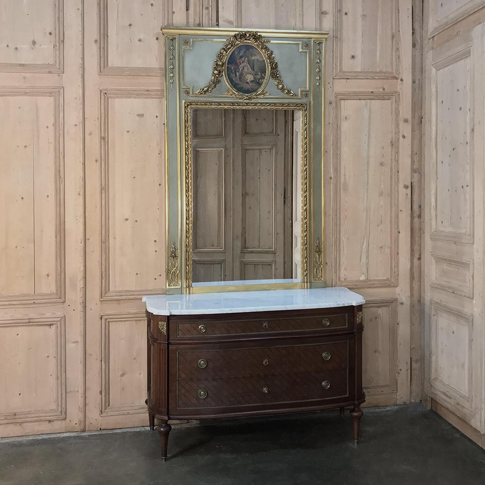 19th century French Louis XVI painted Trumeau is an superb example of Belle Époque period splendor, with bold classical styling in the framework that surrounds both the romantic painting above as well as the generously sized mirror below all