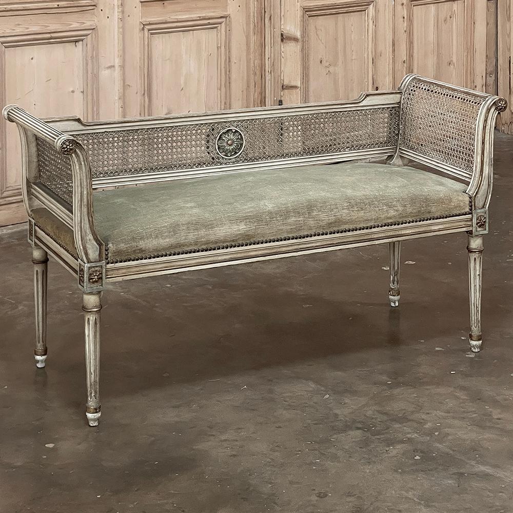 19th Century French Louis XVI Painted Armbench with Cane & Mohair makes a perfect choice in front of a window, on a stairwell landing, in a hallway, or at the foot of the bed!  Hand-crafted from fine hardwood then carved with classic rosettes, it