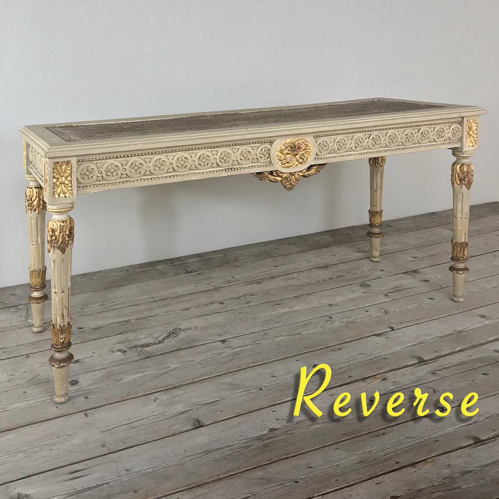 19th century French Louis XVI painted banquette, bench features elaborate hand carved neoclassical motifs including Greek coin, acanthus rosettes and plumes, and foliates all enhanced by the patinaed painted finish with gold highlighting. Caned top