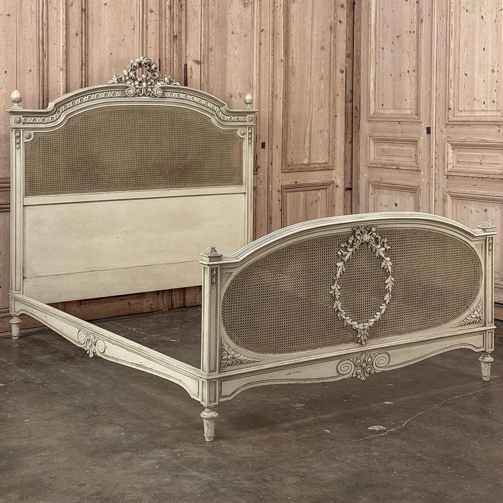 Das französische Ludwig-XVI-Bett aus dem 19. Jahrhundert mit Bemalung ist ein bemerkenswertes Werk der Möbelbaukunst!  Es ist aus Nussbaumholz geschnitzt und zeichnet sich durch seine Kunstfertigkeit aus, die von der Krone des Kopfteils bis zur