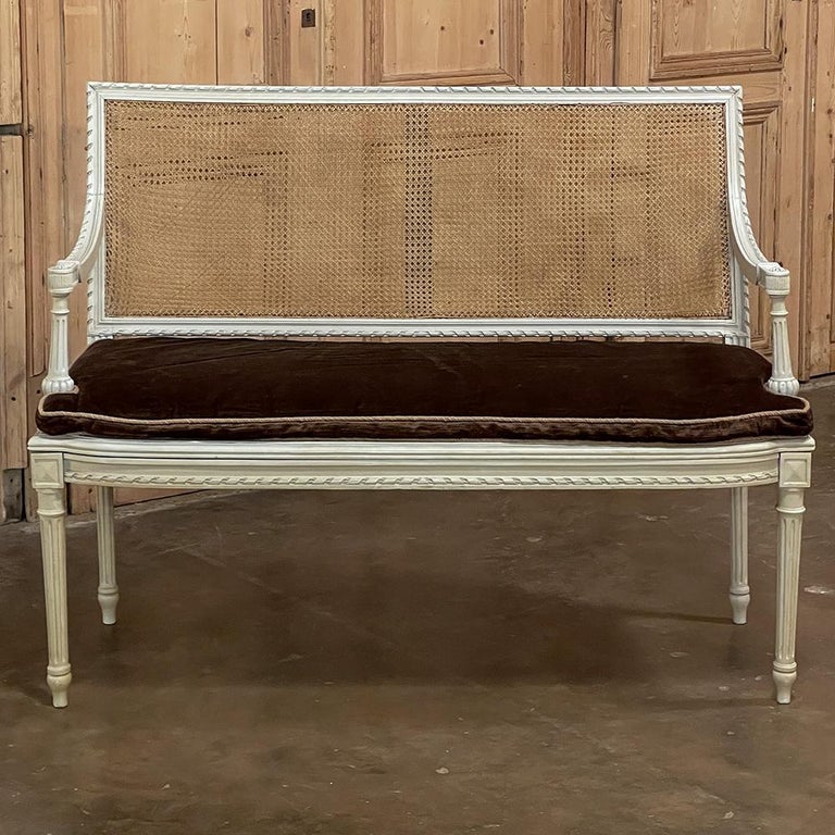 19th century French Louis XVI painted canape with cane & cushion is an excellent choice for an intimate seating group! The combination of neoclassical styling, timeless architecture, and caned seat and seat back produce a light weight, attractive