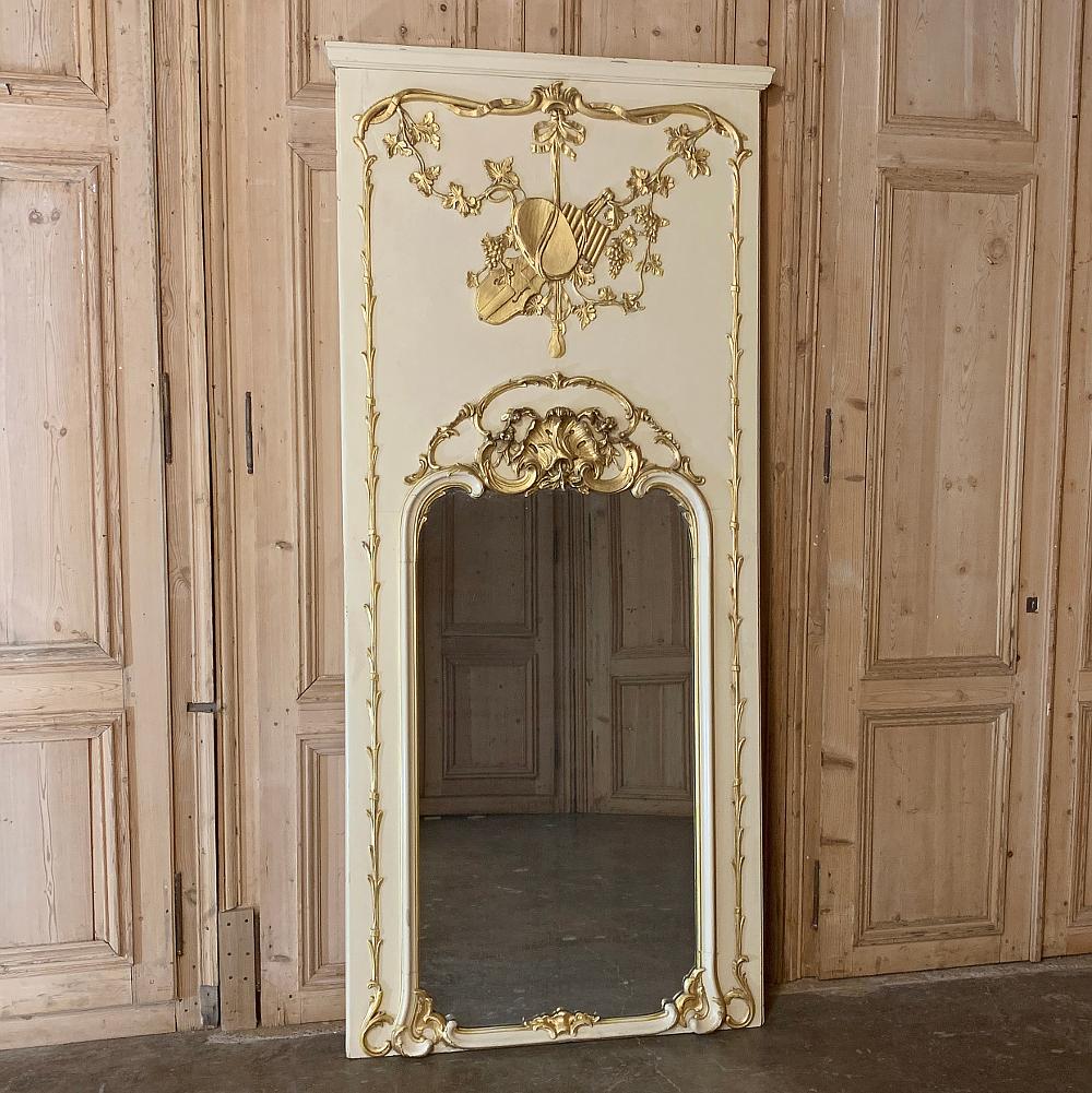 19th Century French Louis XIV Painted Trumeau features classically inspired architecture and elaborate bas relief and molded detail highlighted in gold to complement the warm beige patinaed painted finish of the woodwork.  Unlike typical trumeaux