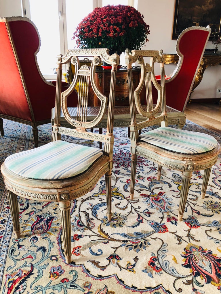 Pair of petite French Louis XVI side chairs made of natural carved wood, hand painted in light green with Lyre backrest. There is also a hand carved and painted bench that matches perfectly the pair,
circa 1890.
