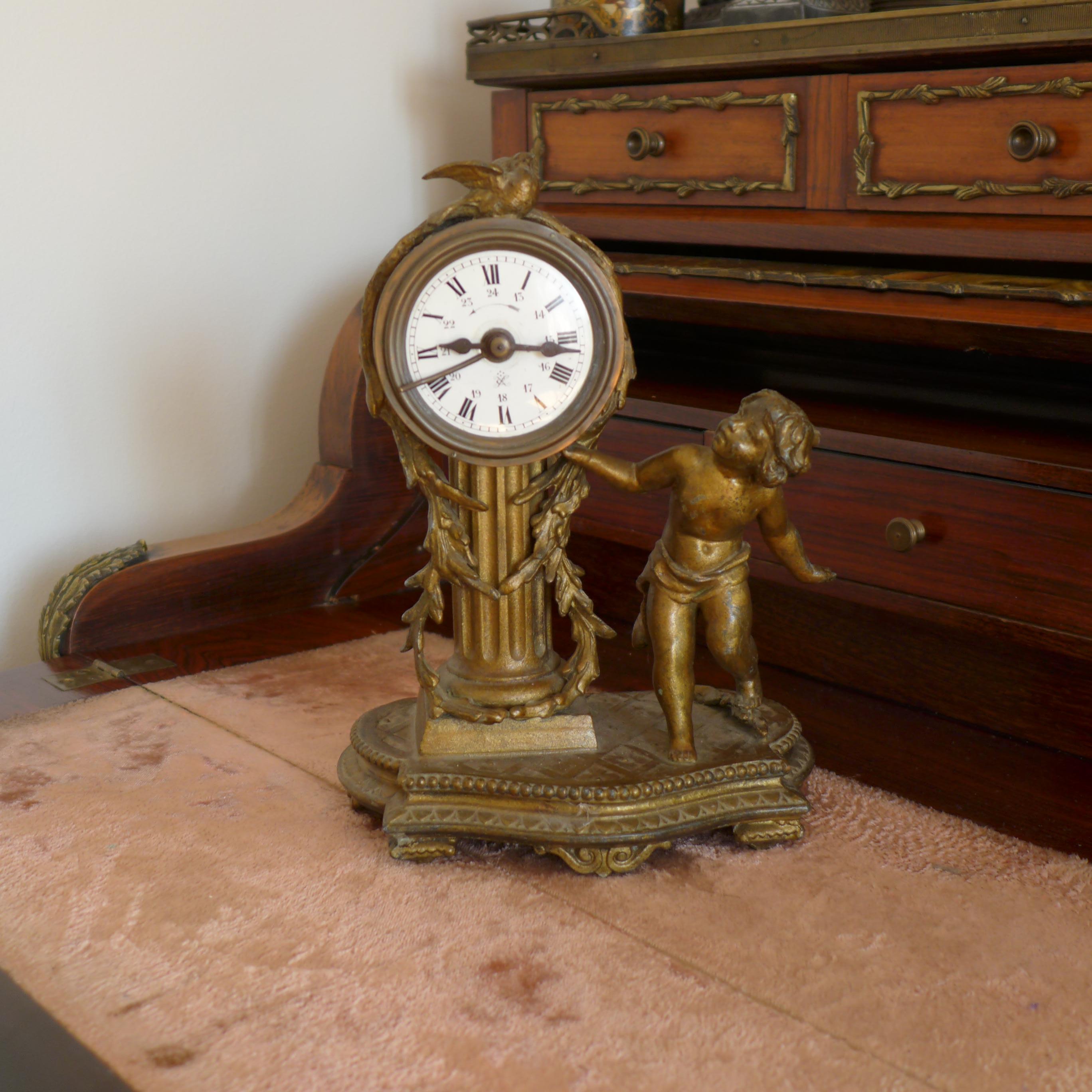 19th century elegant antique desk or mantel clock dated circa 1860. The clock stands on curved feet and features a carved sculpture of a little boy and a bird. The intricate clock mechanism has been cleaned and checked and is in wonderful working