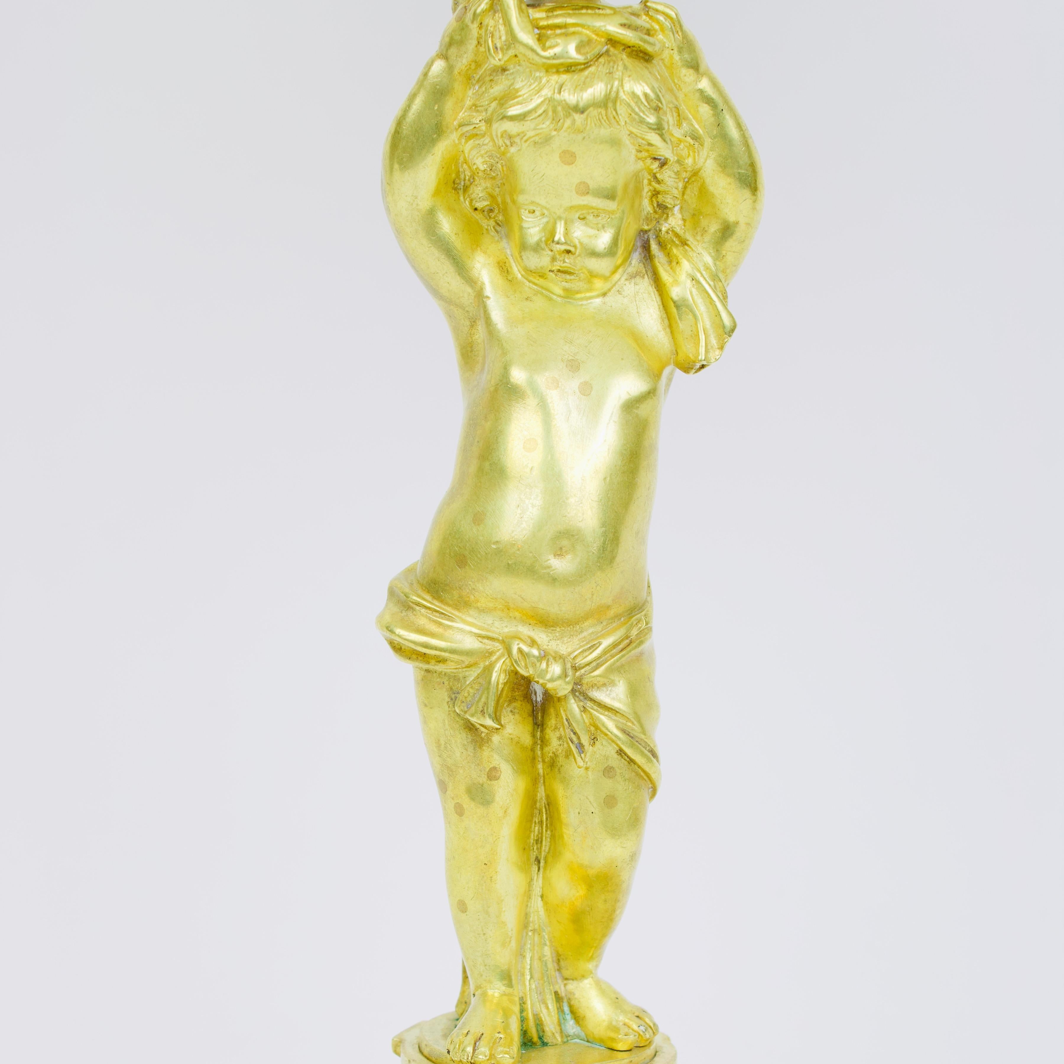 19th Century French Louis XVI porcelain and gilt bronze Putto figure Tazza 

Standing on a circular base featuring neoclassical Louis XVI ornamentation a putto figure with a cloth draped around his hips and holding his arms up in the air. From his