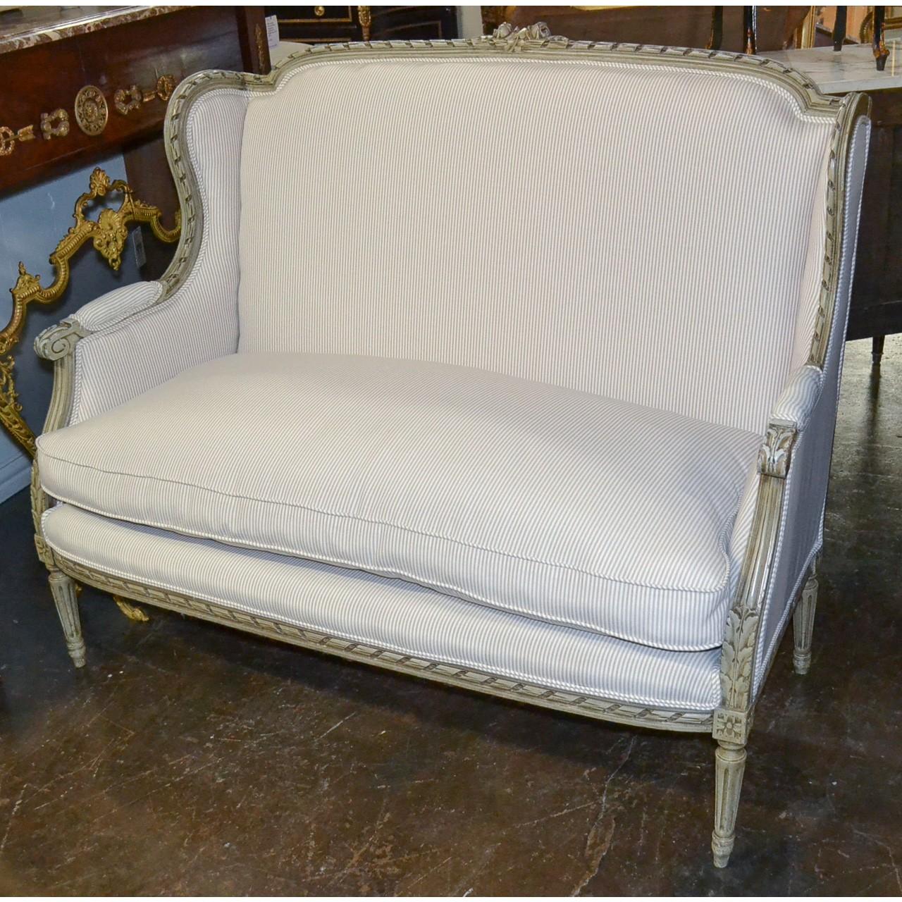 Exceptional 19th century French Louis XVI style sofa or settee with ivory painted patina. The crest hand-carved with rosebuds and leaf sprays. Beautifully contoured arms flow seamlessly to partially upholstered arms. The entire on Classic fluted and