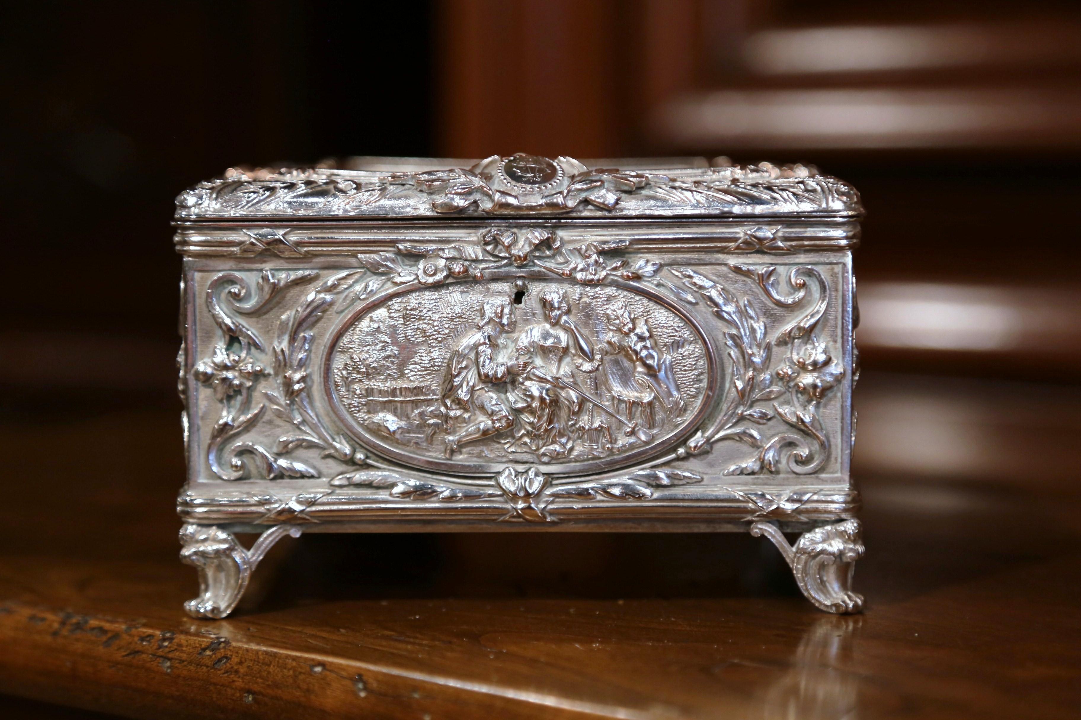 Place this elegant, antique silver coated copper box in your master bath to keep your jewelry safe and organized. Crafted in France, circa 1880, the ornate square casket sits on scroll feet, embellished with four embossed courting scenes on all four