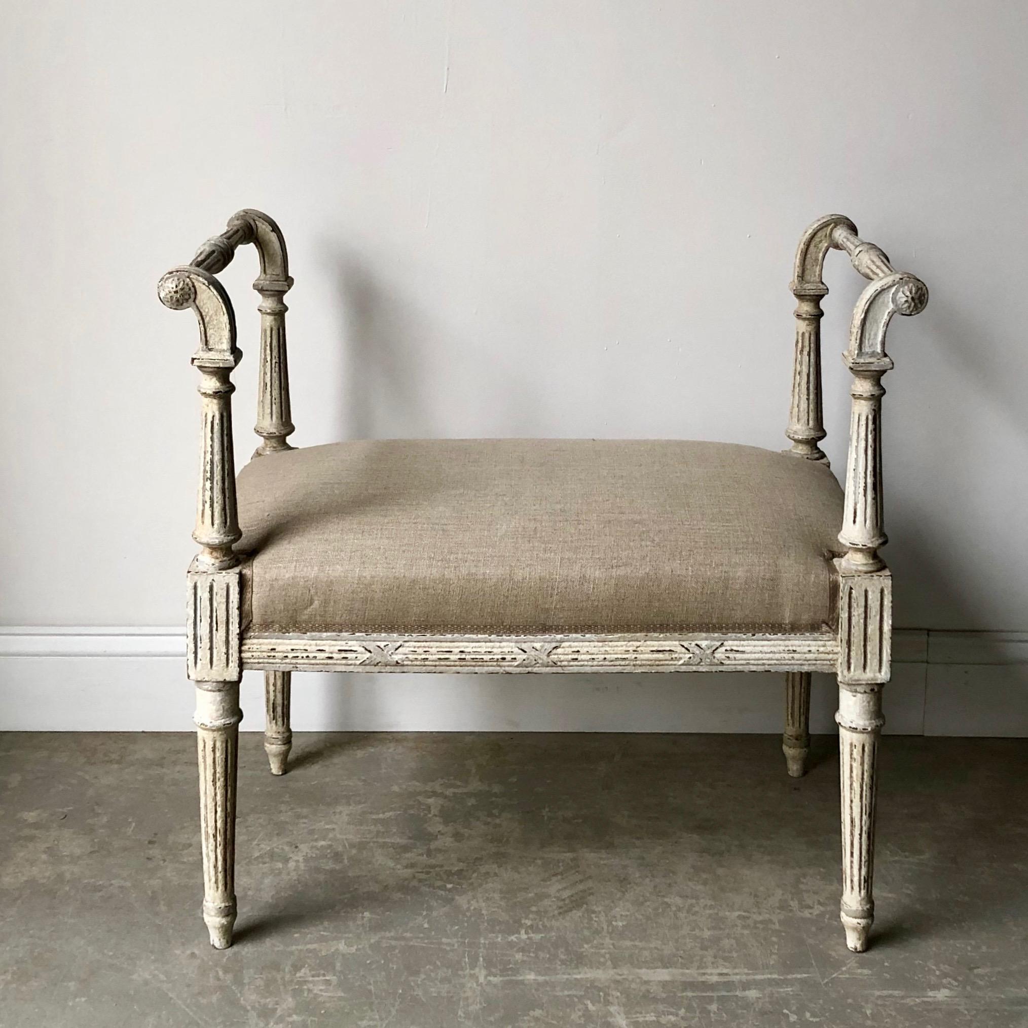 Charming small bench in Louis XVI style, with richly carved armrests and side rails, tapered fluted legs with corner blocks and upholstered seat in linen with beautiful classic gimp. 
More than ever, we selected the best, the rarest, the unusual,