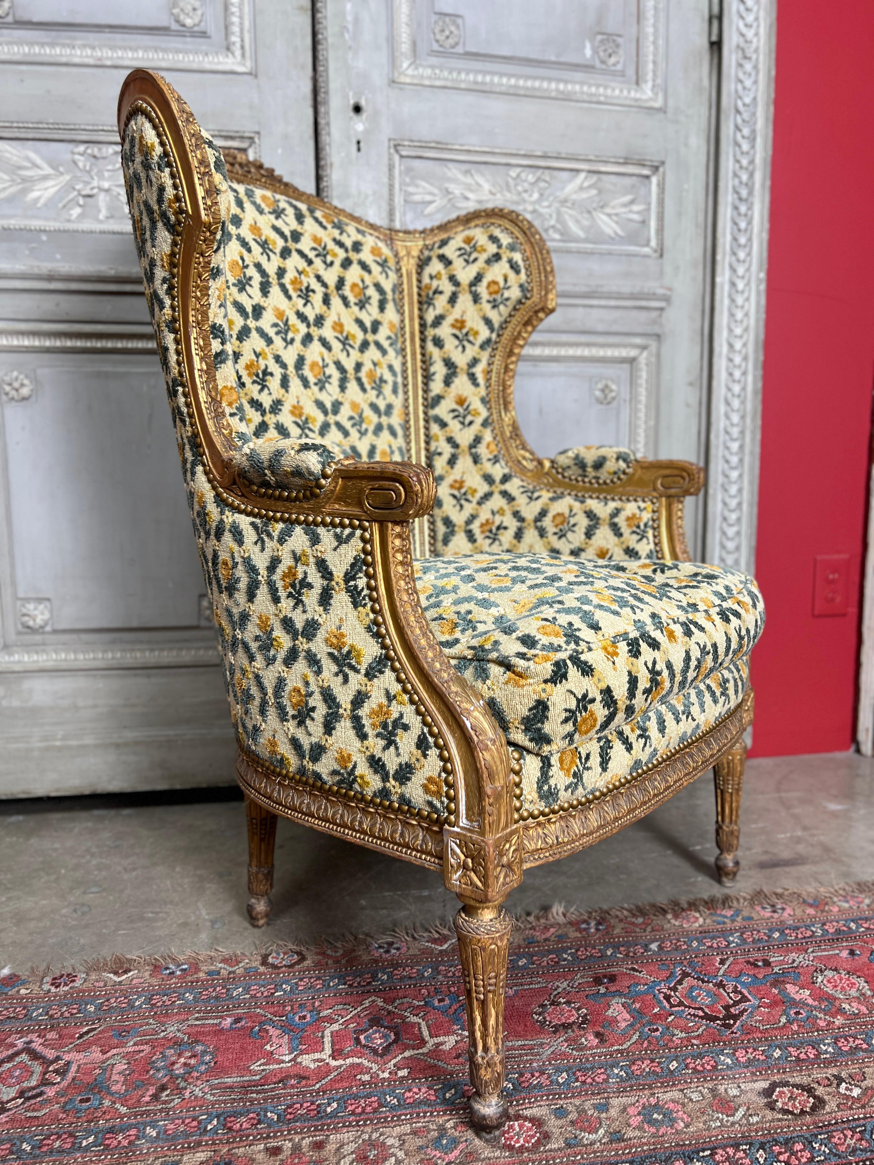 A French carved wood bergere armchair with a gilt finish.  This large bergere dates from the late 19th century and it beautifully carved throughout.  It is upholstered in a fine fabric that is usable but we did not reupholster it and it is price for