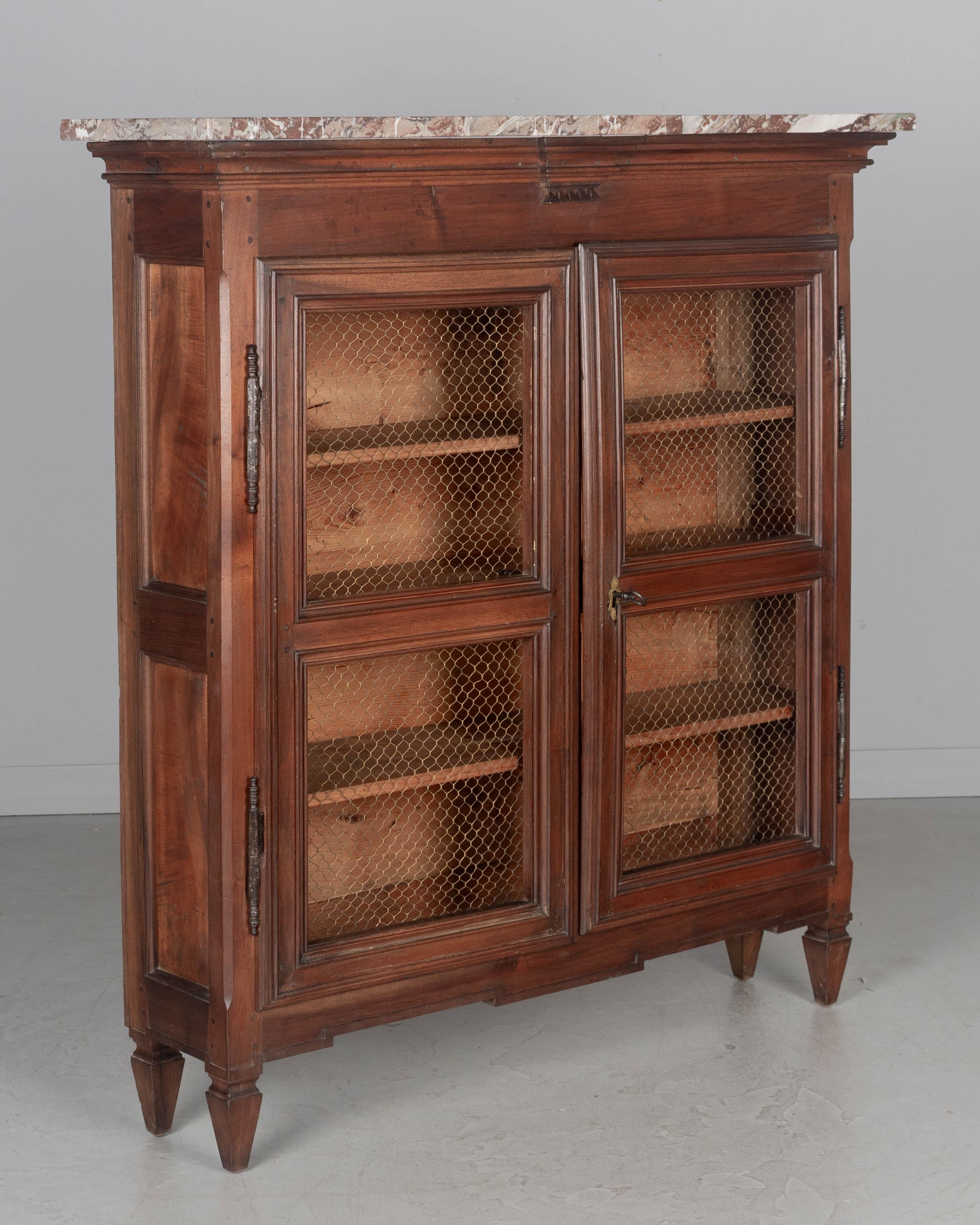 Bibliotheque de style Louis XVI en noyer massif, avec dessus en marbre. Portes de grillage en laiton avec serrure et clé en état de marche. Pieds courts et effilés. Beau plateau en marbre rouge veiné du Languedoc (ajouté ultérieurement). L'intérieur