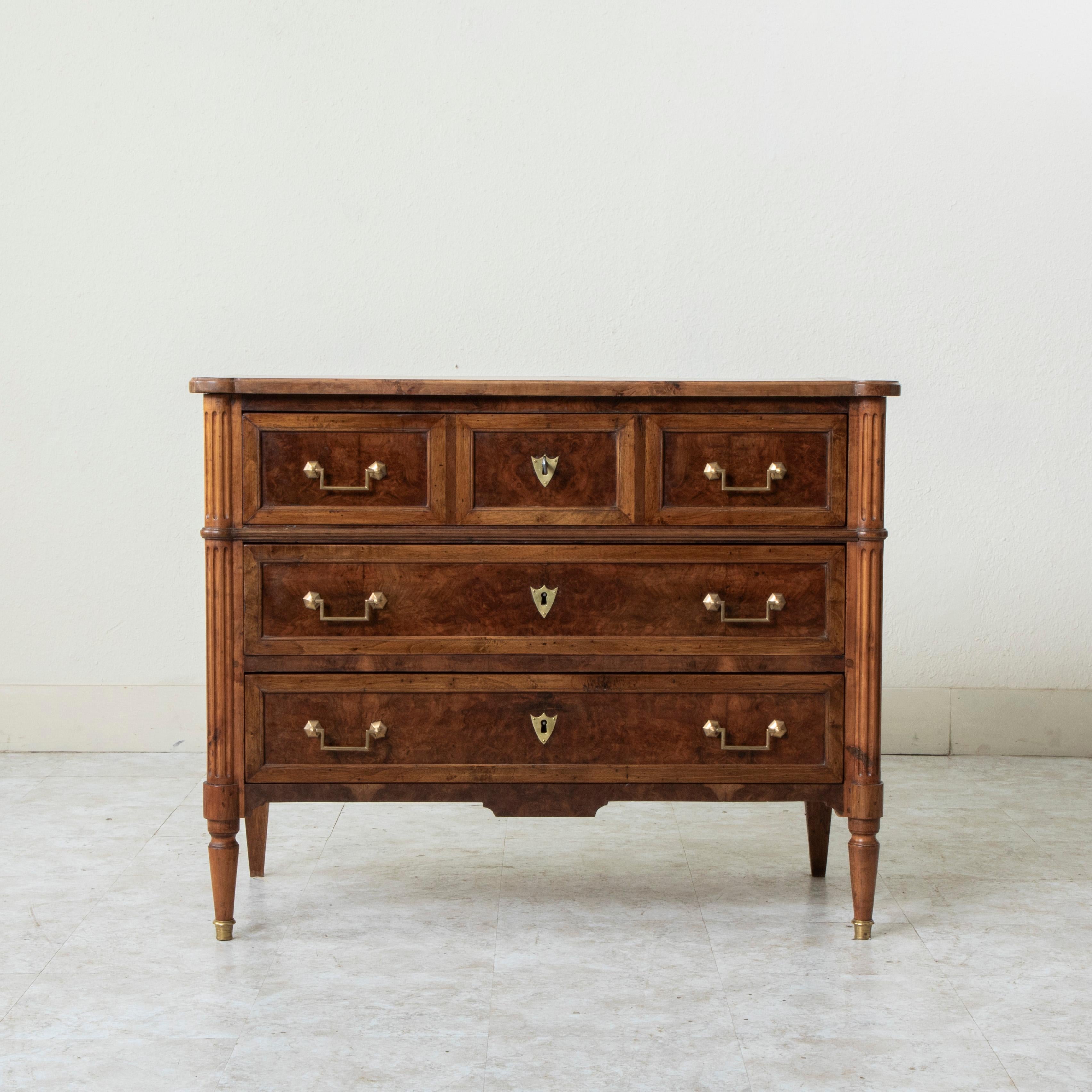 This mid nineteenth century French Louis XVI style commode or chest of drawers features burl walnut panels and fluted rounded corners. Its three drawers of dovetail construction are fitted with classic bronze squared drop handle drawer pulls. The