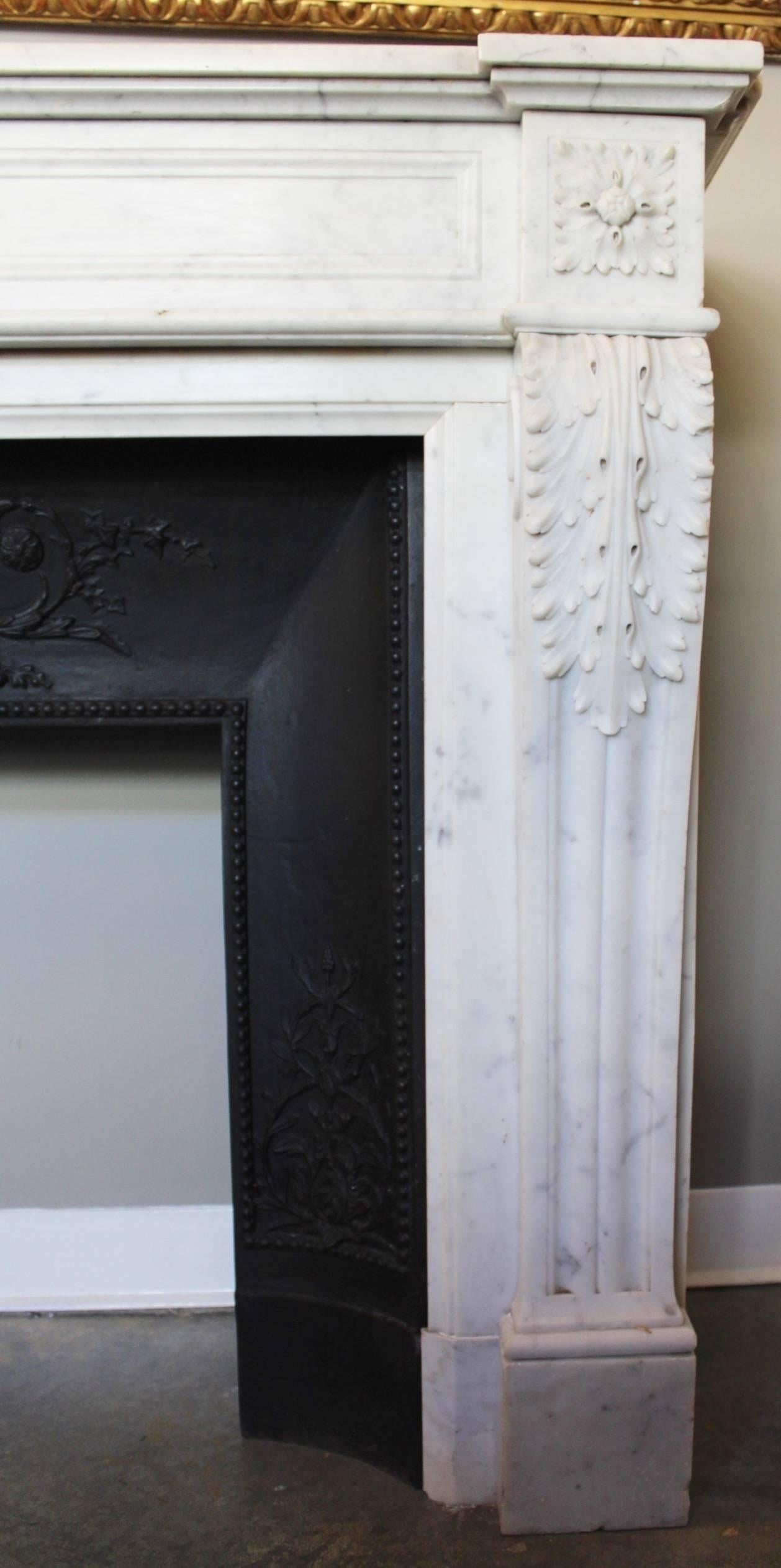 Supremely elegant antique fireplace mantel in white Carrara marble, the quality of the sculptures is enhanced by the starkness of the Carrera. Large carved Acanthus leaves are covering the top of the arched jambs resting on fluted console feet that