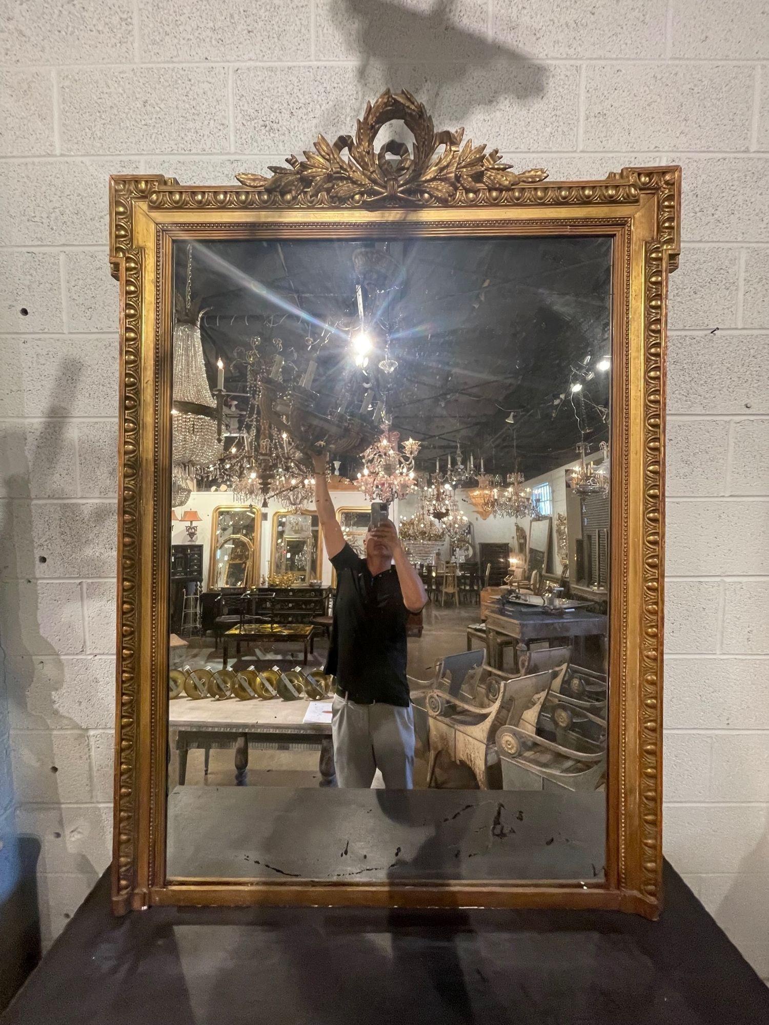 Very fine 19th century French Louis XVI style carved and giltwood mirror. Featuring lovely elaborate carvings including a crest at the top. An exqusite piece for a fine home!