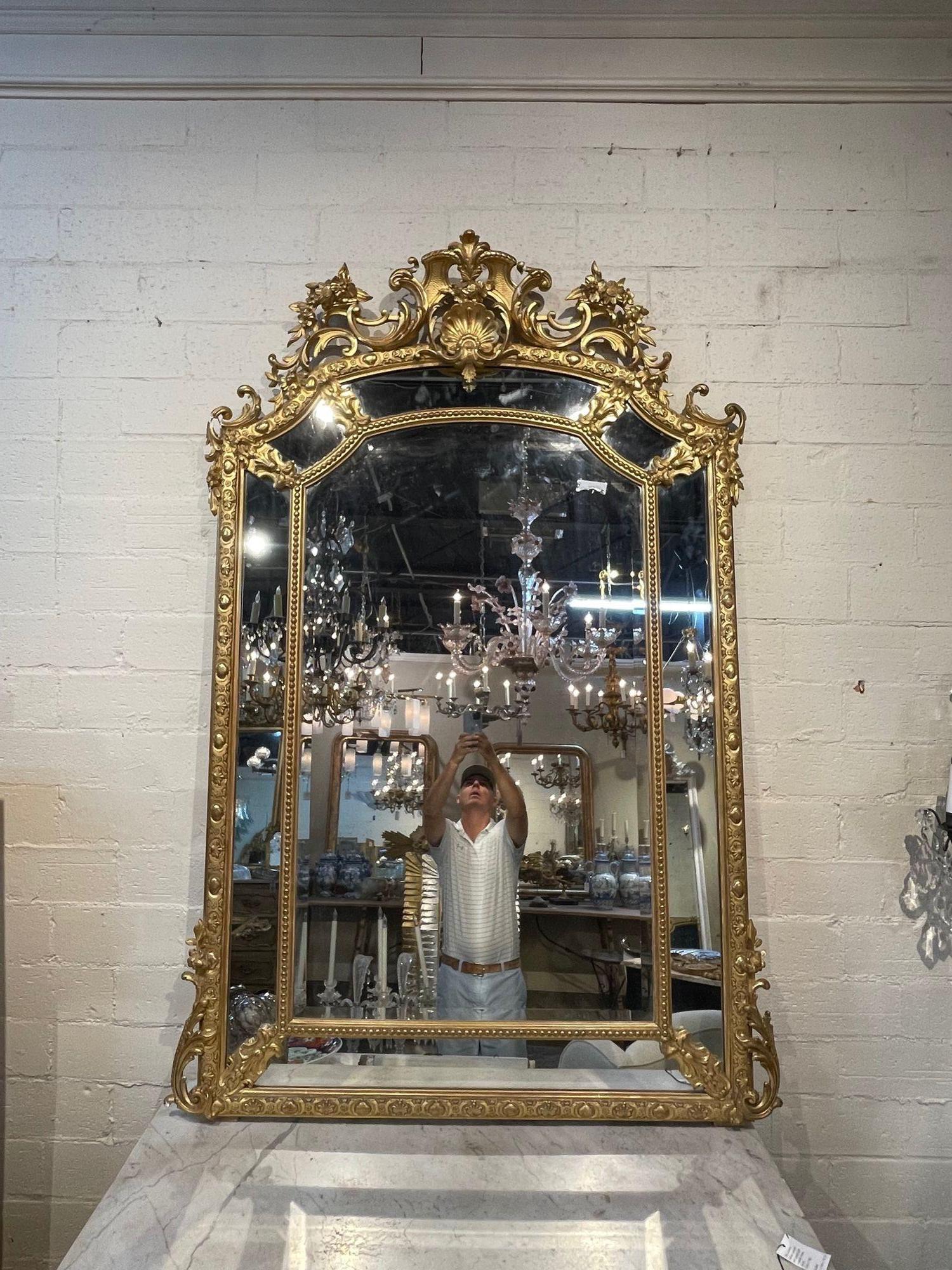 Large scale 19th century French Louis XVI style carved and giltwood mirror. Featuring elaborate carvings including a decorative crest with leaves, flowers and a shell. So elegant!