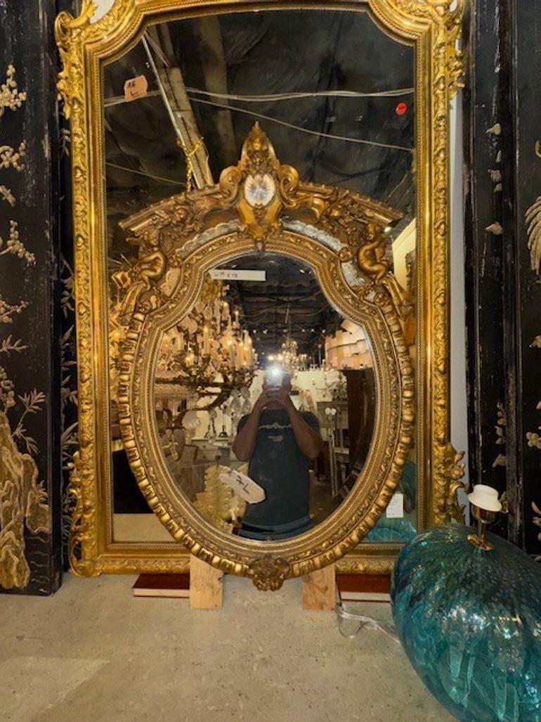 Lo specchio ovale francese del XIX secolo in stile Luigi XVI, intagliato e in legno dorato, presenta un'elegante forma ovale e uno specchio. I dettagli in legno intagliato e dorato aggiungono un tocco di lusso e charme a qualsiasi spazio, rendendolo