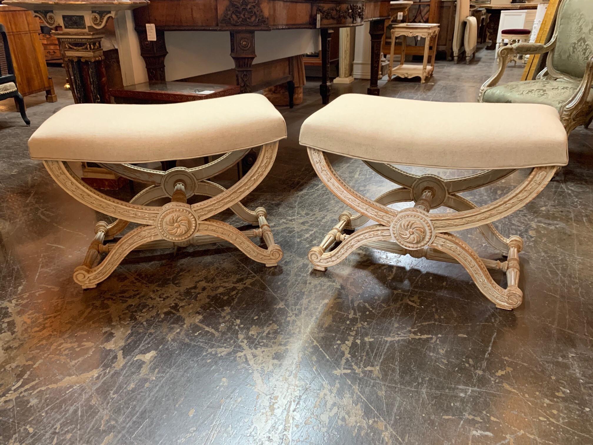 Beautiful 19th century French Louis XVI style carved and painted X form benches. Upholstered in a beige linen with exceptional carving. Fabulous!! Note: Price listed is per item.