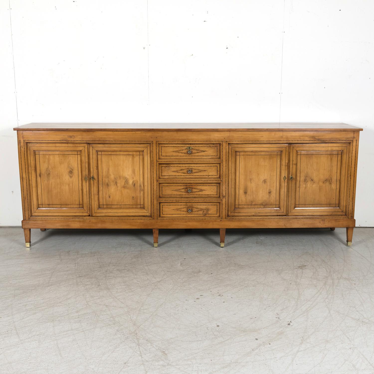 A grand scale 19th century French Provençal Louis XVI style enfilade buffet handcrafted of cherry with fruitwood inlay by master cabinet makers near Avignon, circa 1880s. Having a rectangular plank top over a center bank of four drawers stacked one