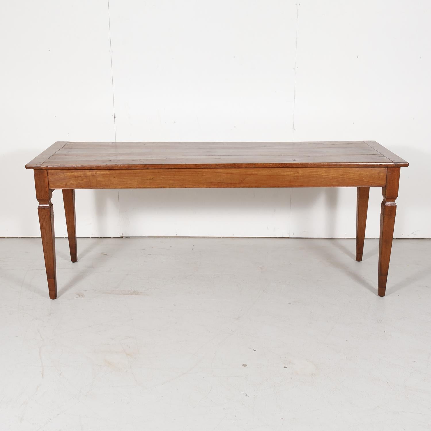 Handsome 19th century French Louis XVI style wild cherrywood farm table or console with a beautiful sun washed patina handcrafted near Brest, a port city in the Finistère department in Brittany, having a rectangular plank top raised on tapered legs