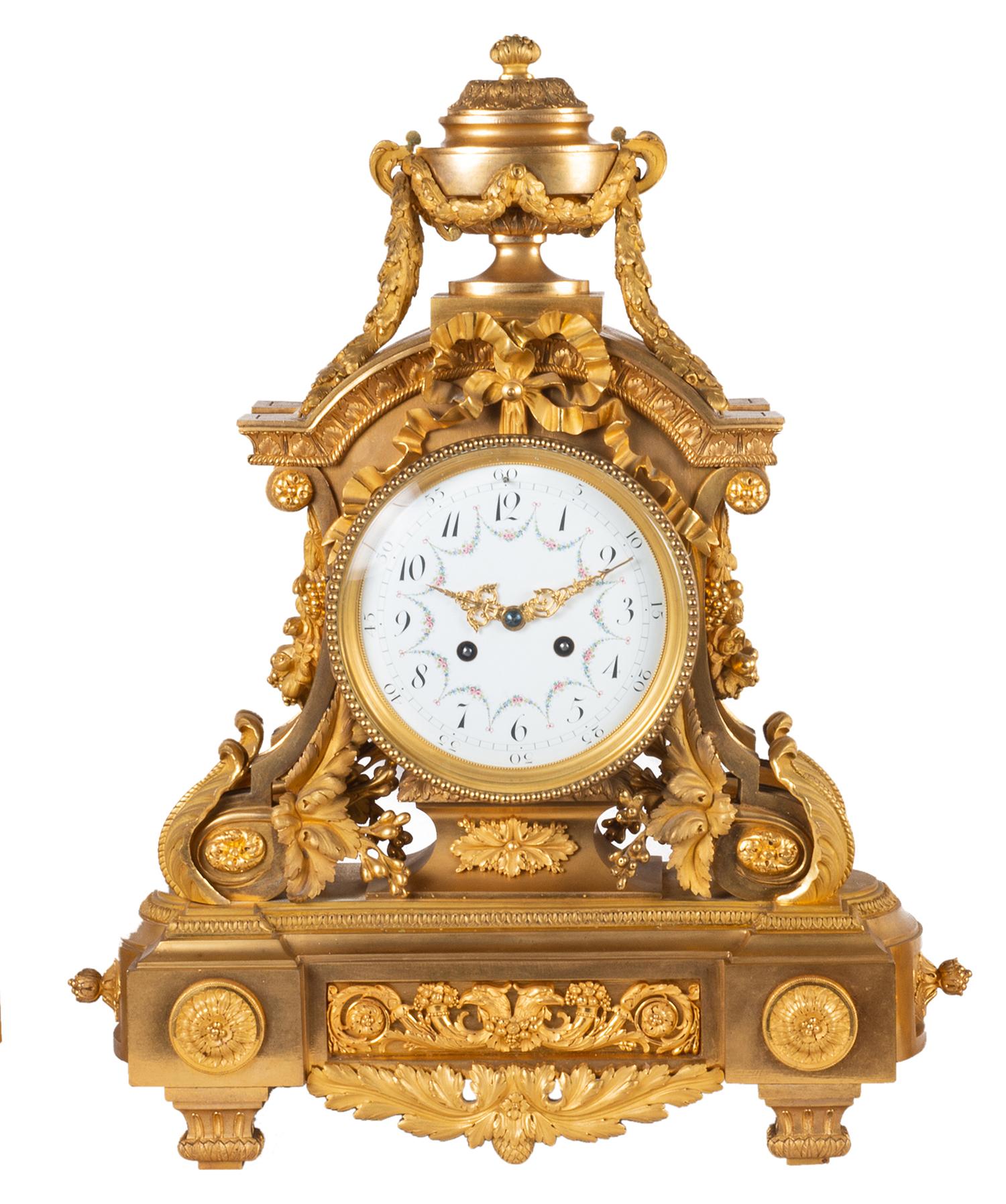 A very good quality 19th century Louis XVI style gilded ormolu clock garniture, the clock having a classical urn finial with garlands, ribbons and foliate decoration. The white enamel clock face with hand painted floral swags, an eight day duration