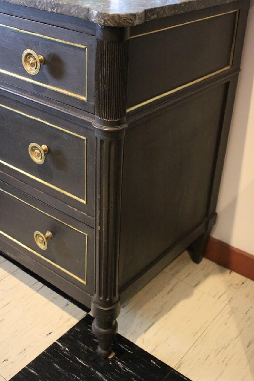 19th century French Louis XVI style commode of oak and mahogany with black marble top, brass cast fittings. Later painted Napoleonic black.