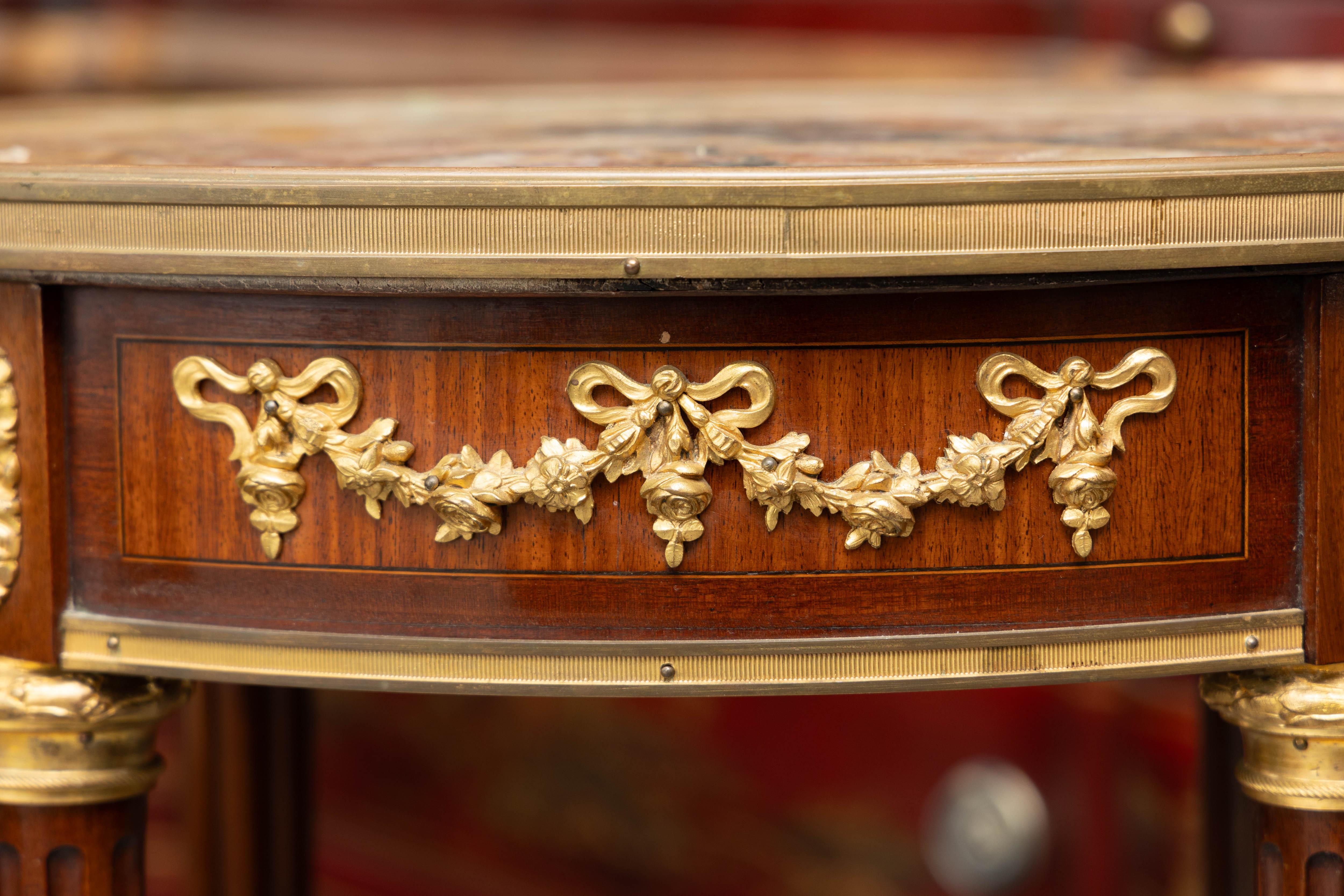 This is a sophisticated 19th century Louis XVI mahogany style end table. The oval Breccia marble top, with gilt bronze band is positioned over a deep frieze containing gilt bronze swags.  The entire top is supported by straight tapering fluted legs