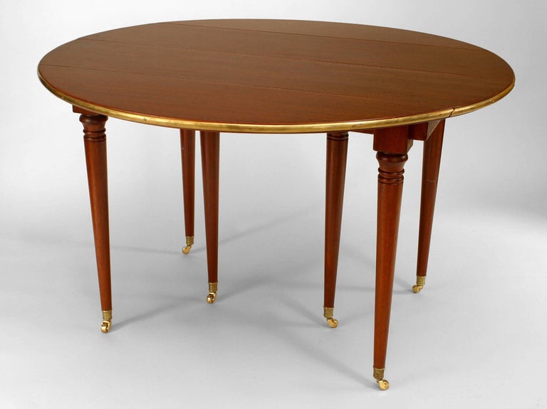 French Louis XVI-Style (19th Century) mahogany round (opened) dining table with drop sides and a brass rim supported on round tapers legs with casters (3 leaves at 18