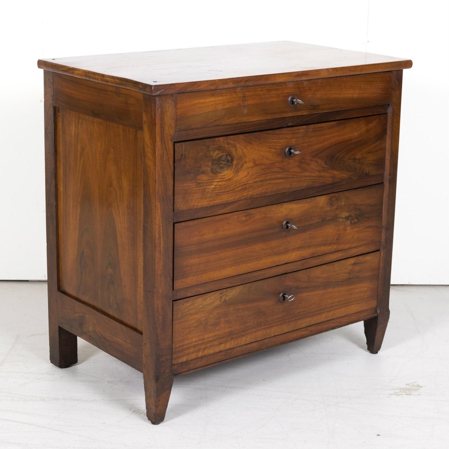 Handsome 19th century French Louis XVI style commode with plank top over four drawers with wood escutcheons and original keys, circa 1890s. Raised on short tapered legs. Handcrafted by rural artisans from solid and beautifully patinated walnut, this