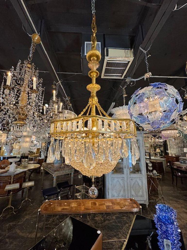 Questo lampadario francese del XIX secolo in stile Luigi XVI è realizzato in bronzo dorato e ornato da accenti di cristallo, con un design lussuoso ed elegante. Lo stile del cestino aggiunge un tocco di raffinatezza, rendendolo un punto focale di