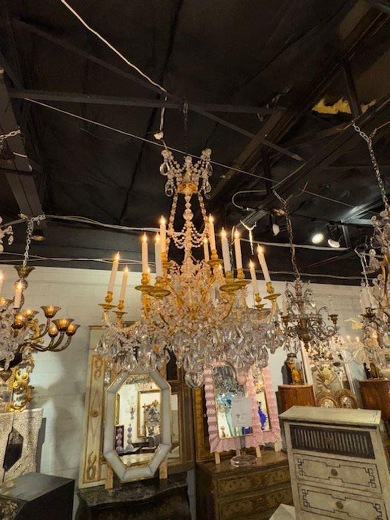 Questo lampadario di grandi dimensioni è un lampadario in stile Luigi XVI francese del XIX secolo, realizzato in bronzo dorato e cristallo. Emana un senso di lusso ed eleganza tipico dell'epoca di Luigi XVI, nota per i suoi design ornati e opulenti.