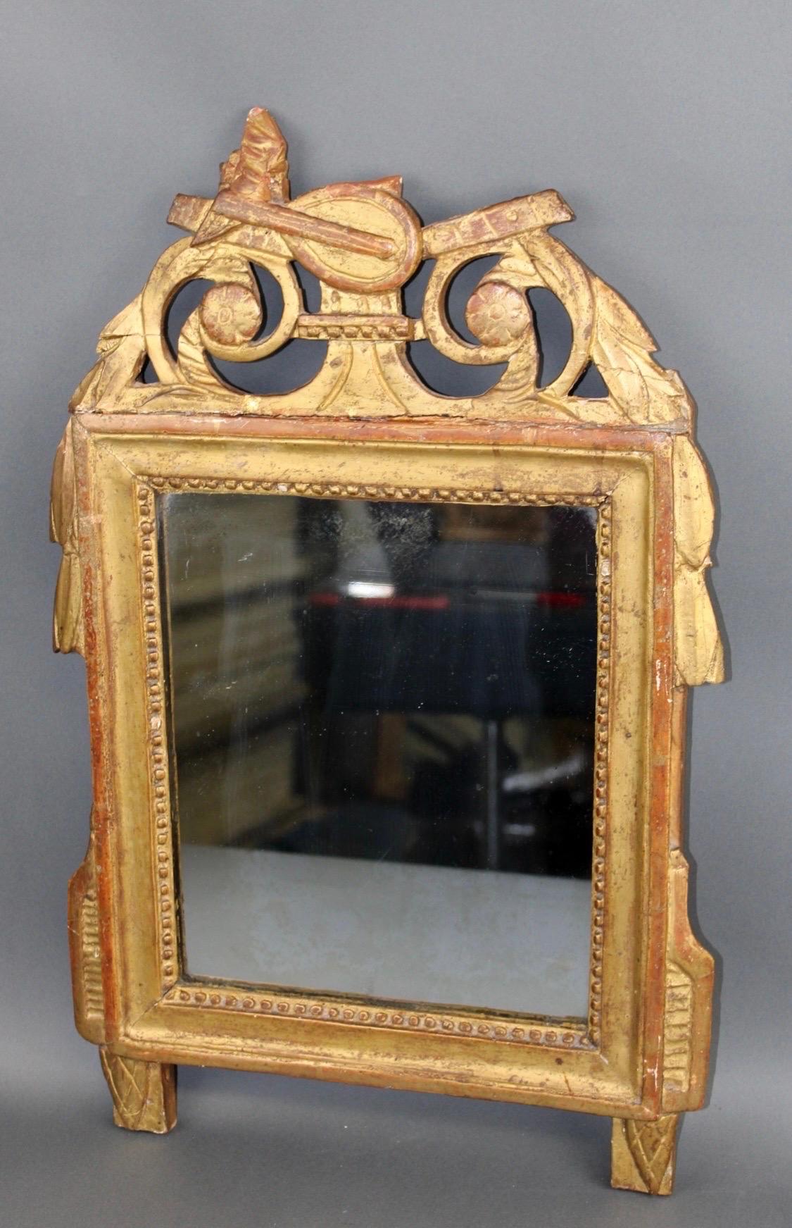 Miroir de style Louis XVI encadré à la feuille d'or et orné d'un écusson sur le thème de la musique. Fin du 19e siècle.
22 