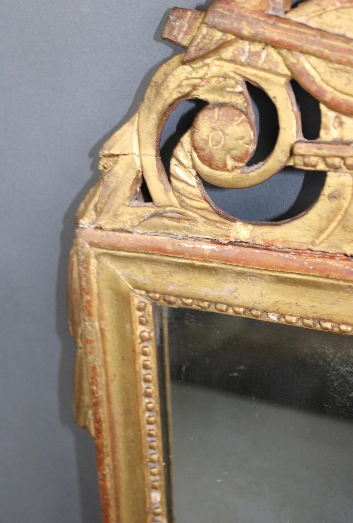 Français Miroir de style Louis XVI encadré de feuilles d'or, 19e siècle, avec écusson à thème musical en vente
