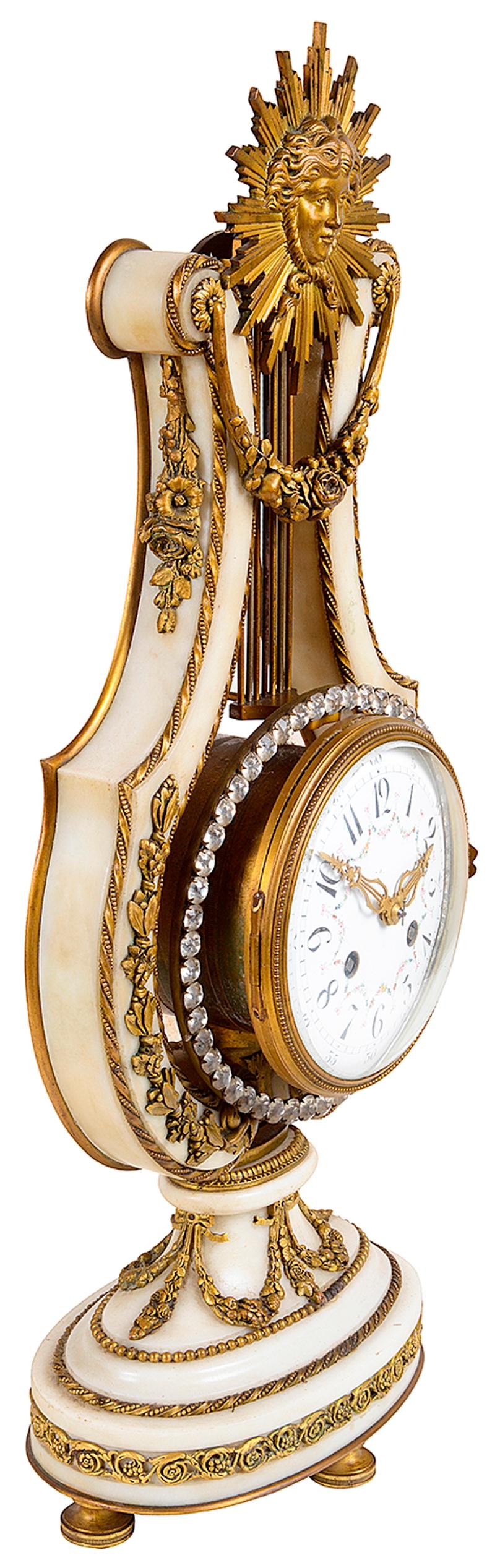 A good quality 19th century French white marble and gilded ormolu mantel clock in the shape of a Lyre. Having a sun burst mount above gilded ormolu garlands of flowers, set into the lyre with a white enamel clock face, an eight day duration