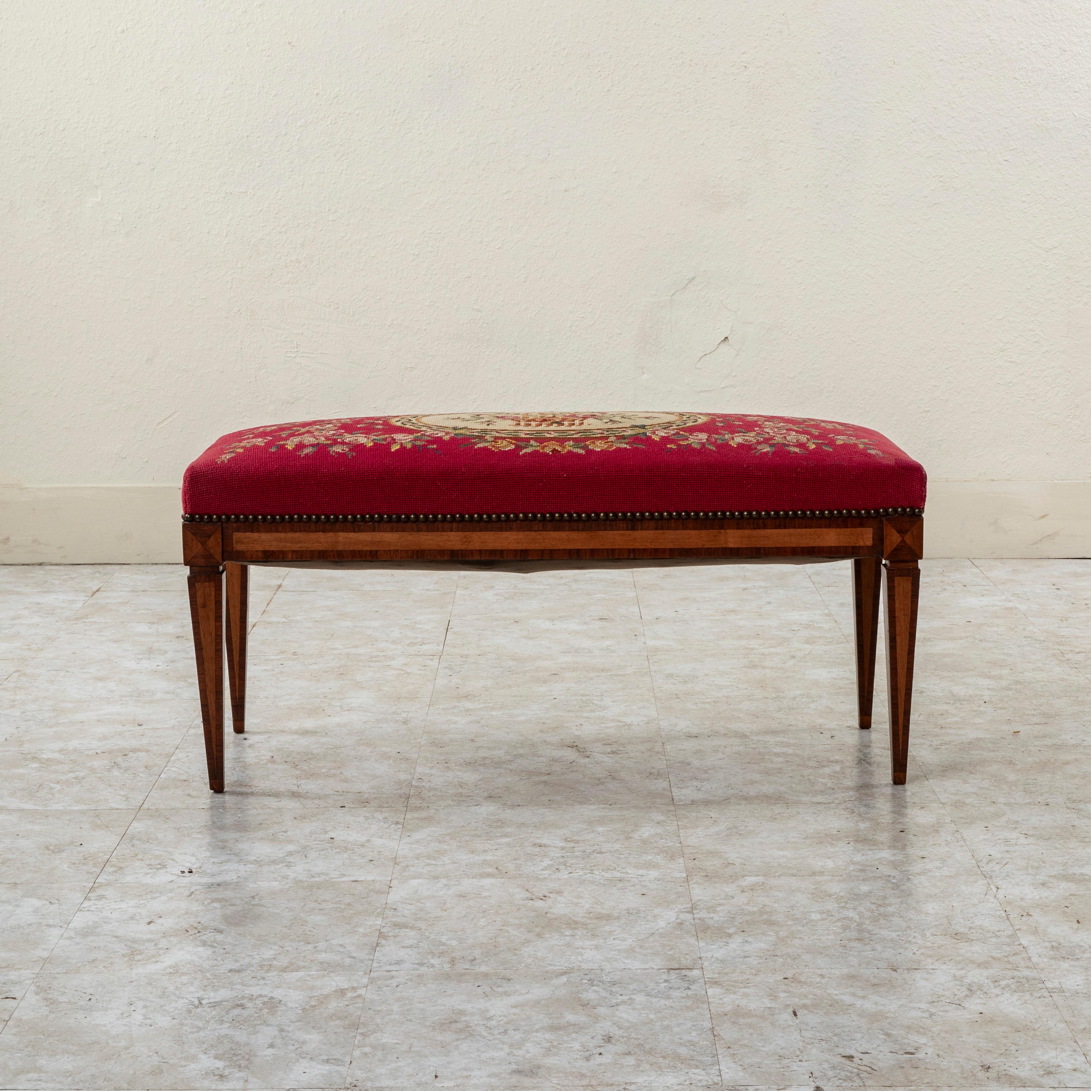 Ce banc en marqueterie de style Louis XVI français de la fin du XIXe siècle présente un cadre composé de panneaux de noyer insérés dans des bordures de bois de rose. Les joints des matrices sont ornés d'un motif en forme de diamant. Tapissé d'un